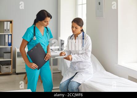 Jeune médecin et infirmière discutant des tests des patients en clinique médicale Banque D'Images