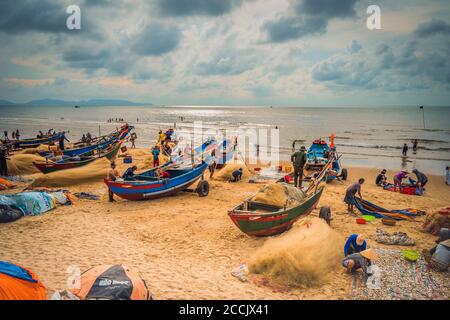 Vung Tau, Vietnam - 22 août 2020: Vue des pêcheurs locaux poussant les bateaux en bois bleu traditionnels de la mer à la côte de façon traditionnelle, ils collectent les poissons Banque D'Images