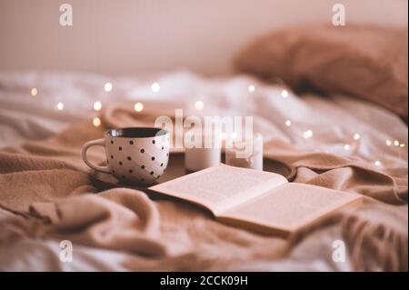 Tasse de café avec livre ouvert et bougies dans le lit de près. Saison d'automne. Bonjour. Mise au point sélective. Banque D'Images
