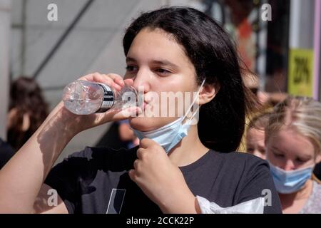 Jeune femme buvant une bouteille d'eau dans la rue de la ville, Royaume-Uni Banque D'Images