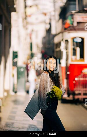 Jeune femme avec bouquet marchant dans la ville Banque D'Images