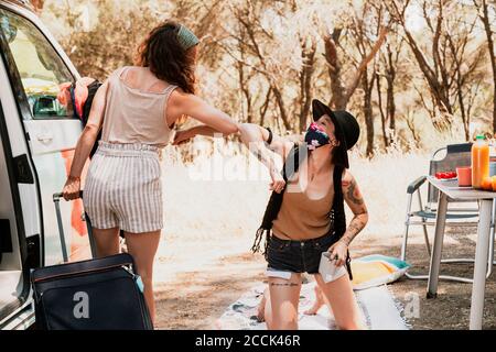 Femmes avec des masques protecteurs saluant avec des boucles d'arc-en-ciel pendant la camionnette de camping-car trajet Banque D'Images