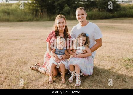 Portrait de parents souriants avec deux filles sur un pré Banque D'Images
