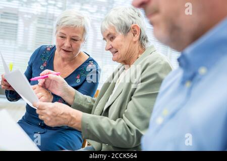 Les aînés du groupe de thérapie dans la maison de retraite rédigeant des notes sur des feuilles de papier Banque D'Images