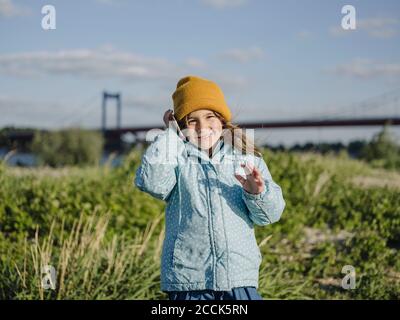 Jolie fille souriante parlant sur un smartphone tout en restant debout atterrir contre le ciel Banque D'Images