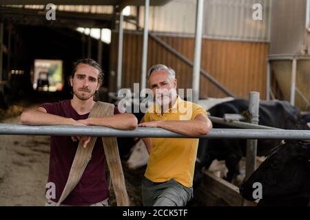 Portrait d'un agriculteur adulte avec son fils adulte à la maison de vache sur une ferme Banque D'Images