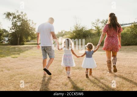 Famille marchant sur un pré en contre-jour Banque D'Images