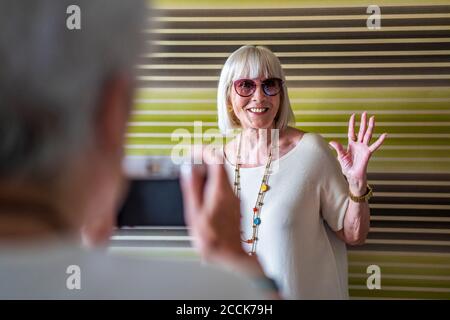 Femme âgée photographiant une amie élégante contre un mur à la maison Banque D'Images