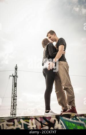 Couple adolescent embrassant sur un mur de graffiti Banque D'Images