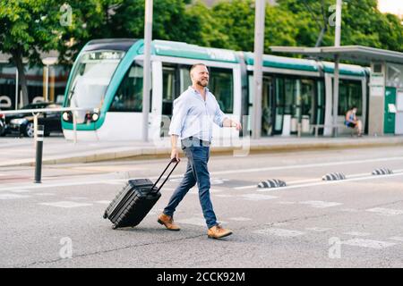 Homme d'affaires avec porte-bagages à roulettes rue dans la ville Banque D'Images