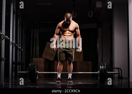 Athlète musclé se préparant à lever la barbell. Entraîneur CrossFit dans un studio de fitness. Banque D'Images