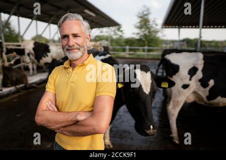 Portrait d'un fermier mûr confiant à la maison de vache sur une ferme Banque D'Images