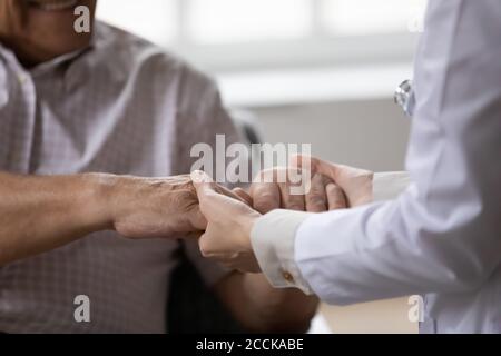 Gros plan jeune femme médecin tenant les mains d'un homme âgé. Banque D'Images