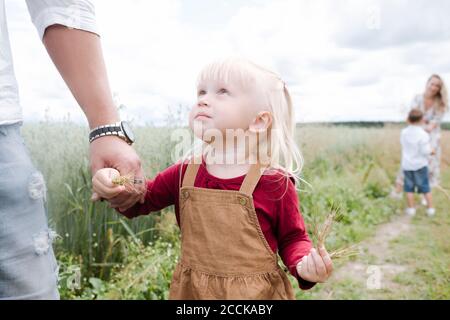 Jolie fille regardant le père tout en se tenant sur le terrain contre ciel Banque D'Images