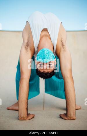 Jeune homme portant un masque pratiquant la pose de roue sur une rampe de sport Banque D'Images