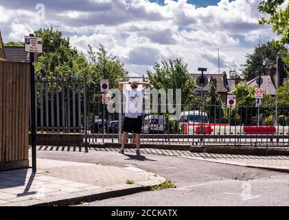 Un homme se tient avec ses mains sur la tête dans un t-shirt et un short, regardant un ciel nuageux menaçant. Banque D'Images