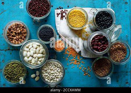 Divers haricots et lentilles en pots sur une surface en bois rustique bleu Banque D'Images