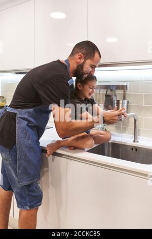 Père et fille se lavant les mains dans l'évier de cuisine à la maison Banque D'Images