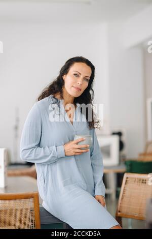 Femme propriétaire tenant une tasse de café assis sur une table restaurant Banque D'Images