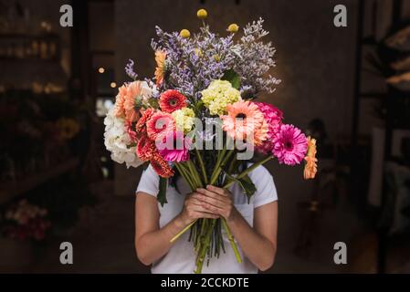 Fleuriste féminin tenant des fleurs colorées tout en étant debout dans le magasin Banque D'Images