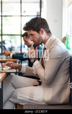 Homme d'affaires pensant en utilisant un ordinateur portable dans le restaurant Banque D'Images