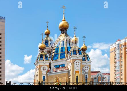 Dômes d'or d'une église chrétienne sur des façades de toit en verre au milieu d'une zone résidentielle urbaine contre un ciel bleu nuageux. Banque D'Images