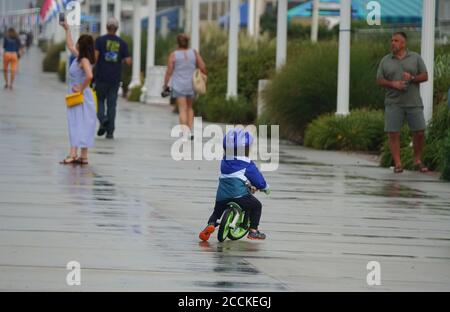 Virginia Beach, États-Unis - 29 juin 2020 - UN petit garçon qui fait du vélo sur la promenade pendant une journée d'été humide Banque D'Images