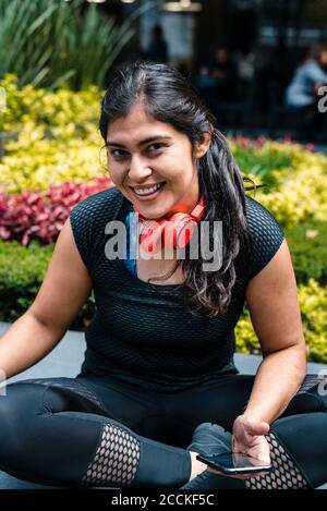 Jeune femme pendant la pause après l'entraînement assis sur le banc Banque D'Images