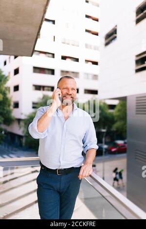 Homme d'affaires parlant sur le téléphone portable tout en étant debout dans le balcon de bureau Banque D'Images