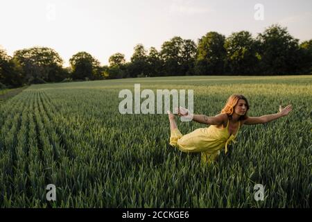 Jeune femme debout dans un champ de céréales avec des bras étirés Banque D'Images