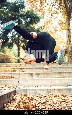 Un jeune homme sautant au-dessus des feuilles d'automne dans le parc