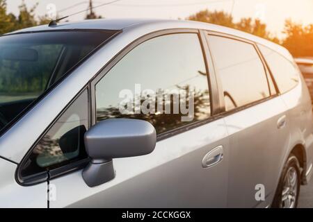 Vue avant d'une voiture japonaise dans le corps de un hayon sur le côté d'une station familiale argentée dans un parking avec des arbres verts après avoir été lavé rea Banque D'Images