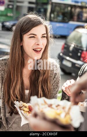 Portrait d'une adolescente en compagnie d'amis la ville ayant un snack Banque D'Images