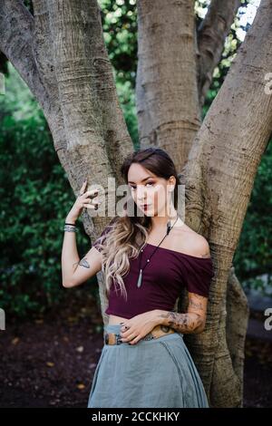 Portrait d'une jeune femme penchée sur un arbre dans le parc Banque D'Images