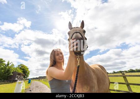 Une jeune femme qui a caressé son cheval dans une ferme Banque D'Images