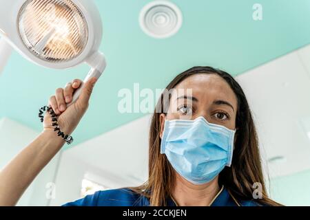 Médecin avec lumière réglable travaillant dans la clinique du dentiste Banque D'Images