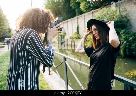 Homme photographiant sa petite amie avec un appareil photo tout en se tenant dans le parc Banque D'Images