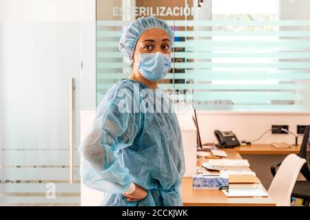 Dentiste féminin regardant loin en étant debout au bureau Banque D'Images