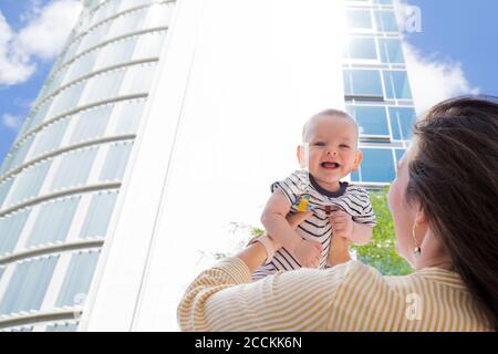 Mère levant son bébé garçon dans la ville Banque D'Images