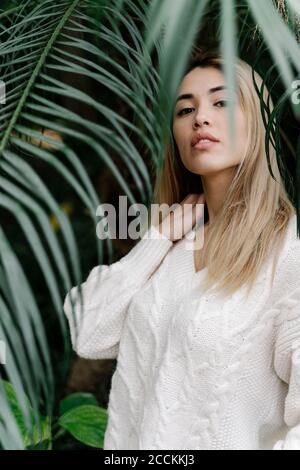 Portrait d'une femme blonde souriante aux feuilles de palmier Banque D'Images