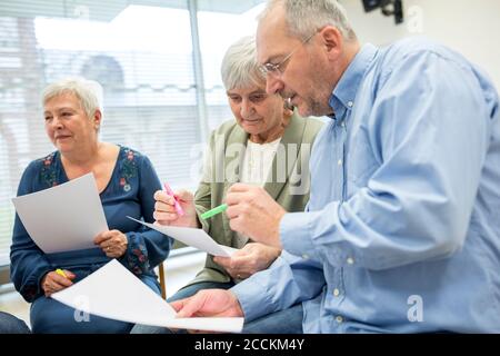 Les aînés du groupe de thérapie dans la maison de retraite rédigeant des notes sur des feuilles de papier Banque D'Images
