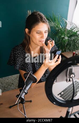 Jeune femme faisant un tutoriel vidéo de maquillage Banque D'Images