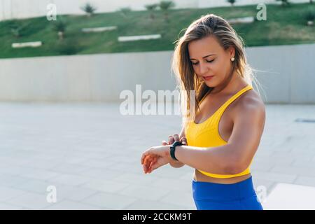 Jeune femme blonde vérifiant la montre intelligente Banque D'Images