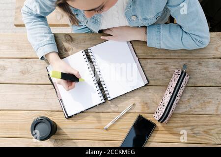 Étudiant avec stylo feutre et livre à table Banque D'Images