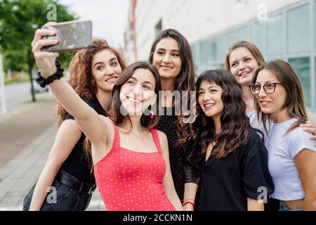 Des amies emportant un selfie avec un smartphone tout en restant debout ville Banque D'Images
