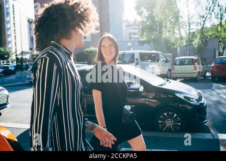 Couple parlant en marchant dans la rue de la ville pendant la journée ensoleillée Banque D'Images