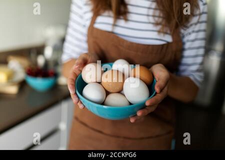Gros plan de la jeune femme tenant des œufs dans la cuisine à la maison Banque D'Images