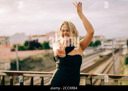Femme joyeuse montrant le signe de la paix dans la ville Banque D'Images