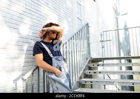 Homme se cachant le visage en se tenant sur l'escalier Banque D'Images