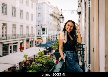 Jeune femme souriante se penchée sur les balustrades de balcon Banque D'Images